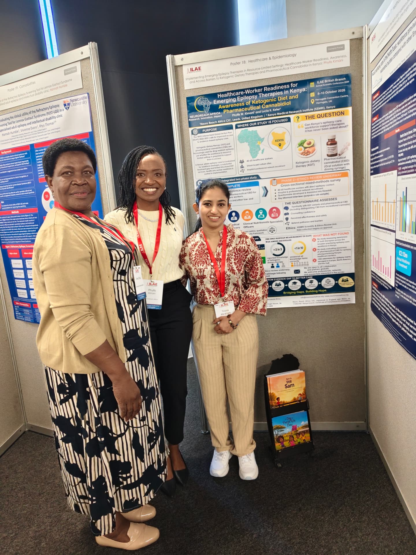Phyllis with fellow delegates beside her poster and the Friends Series books