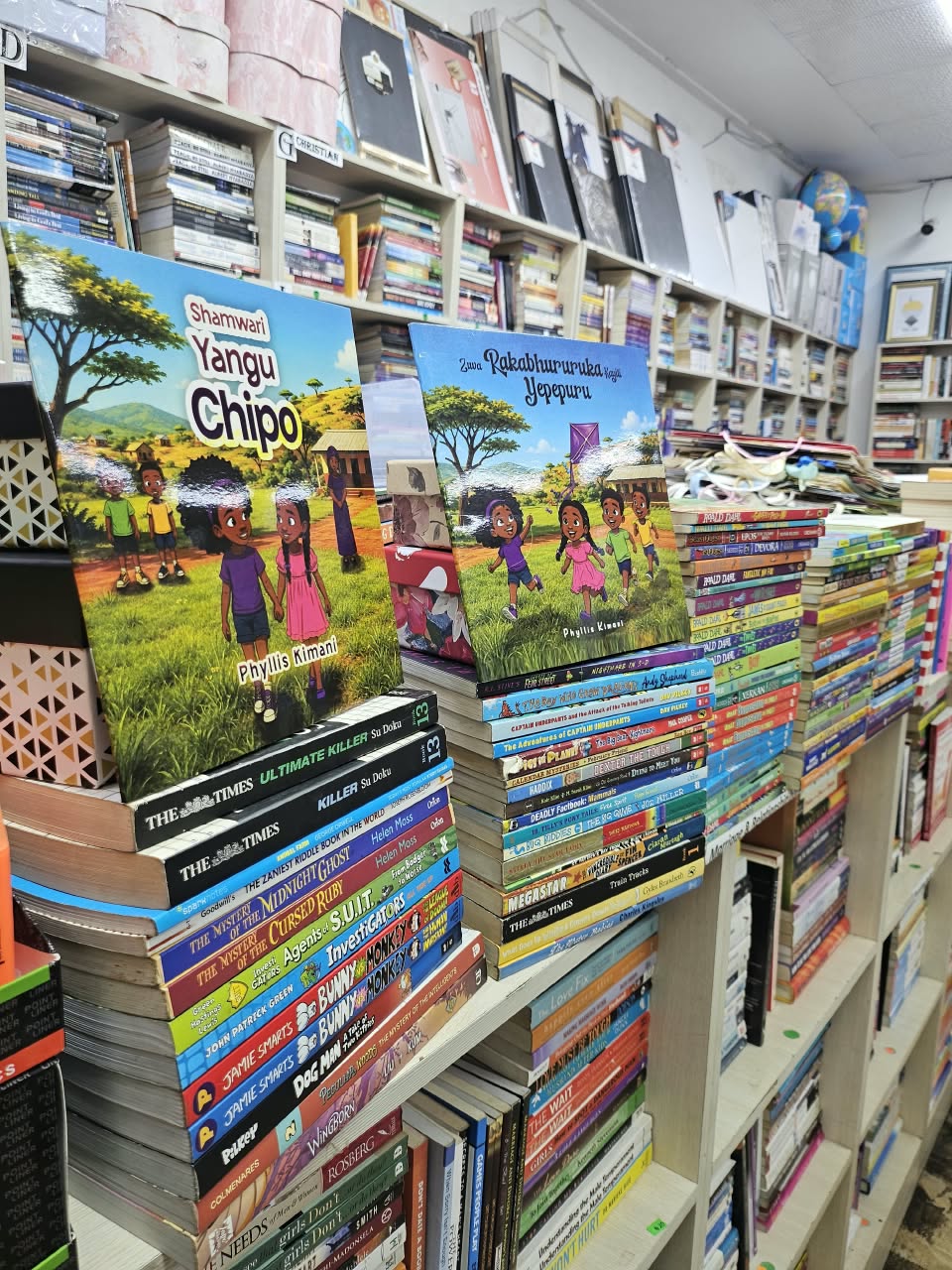 Both Shona titles displayed among children's books on the bookshop shelves.